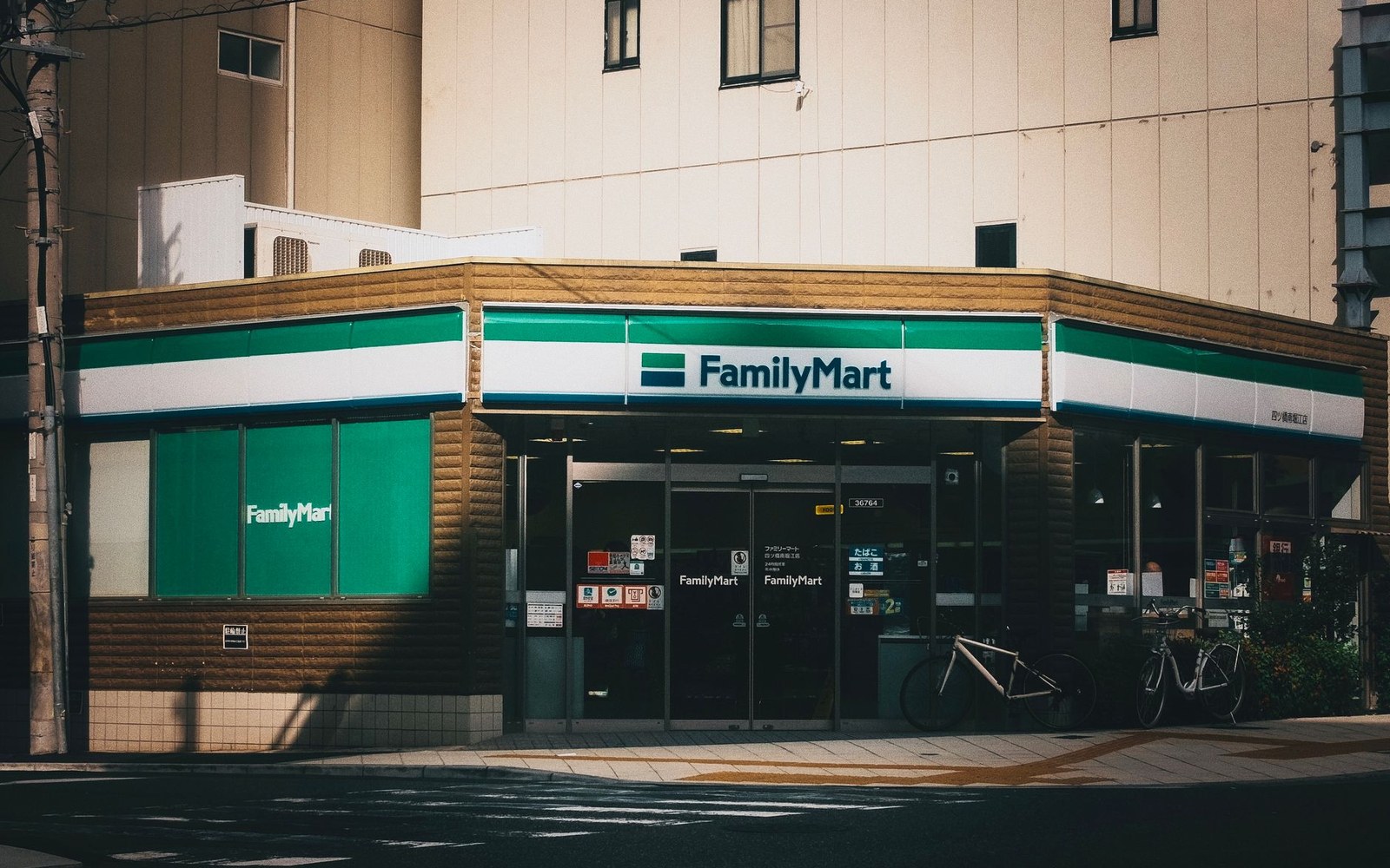 FamilyMart convenience store storefront on a street corner with bicycles parked outside